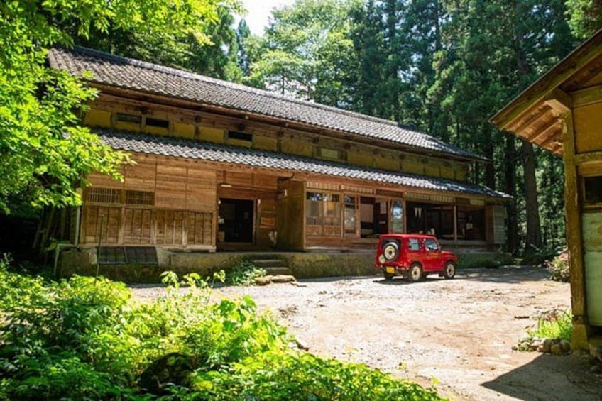 A traditional wooden building with a red car parked in front. 2