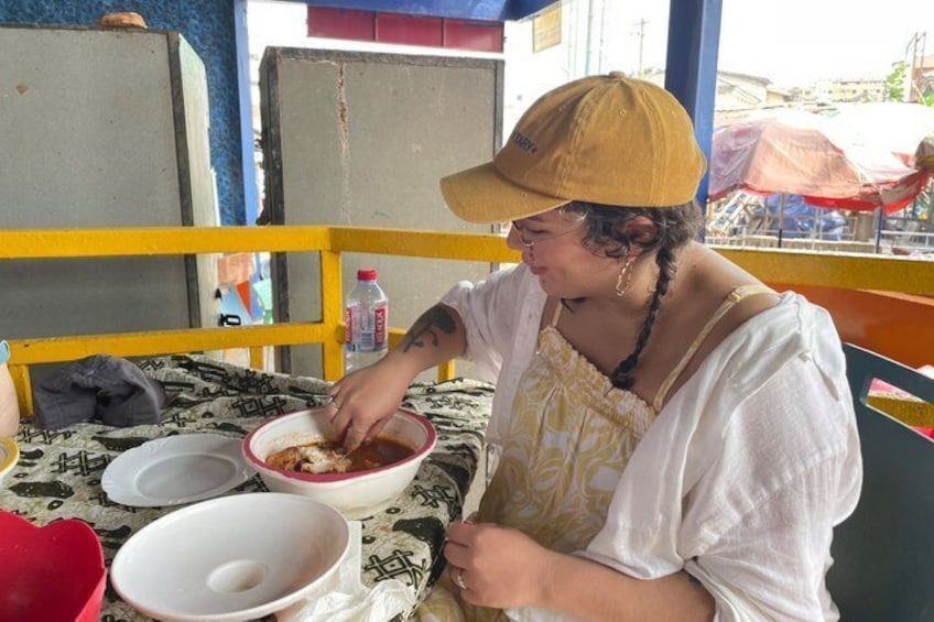 A person eating at an outdoor table with bowls and a bottle. 4