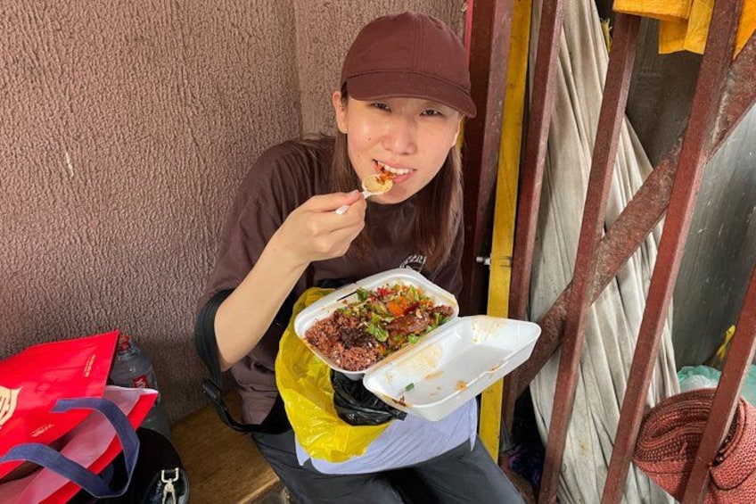 Una persona sentada a una mesa con comida, una bolsa roja y una bolsa amarilla en el suelo. 3