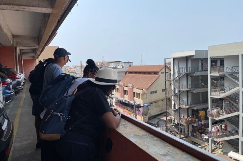 A balcony overlooking a cityscape with parked cars and buildings. 3