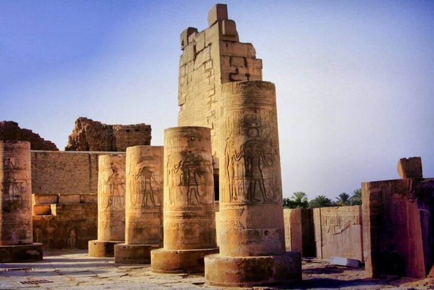 Ancient Egyptian columns with hieroglyphics, set against a clear sky. 2