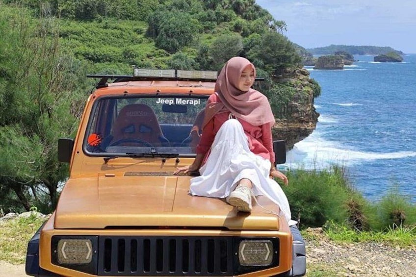 Un Jeep Merapi est garé sur une route côtière, avec des falaises et l’océan en arrière-plan. 4
