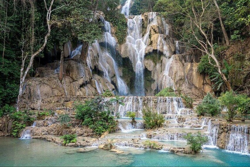 A multi-tiered waterfall cascading into a turquoise pool surrounded by lush greenery. 3