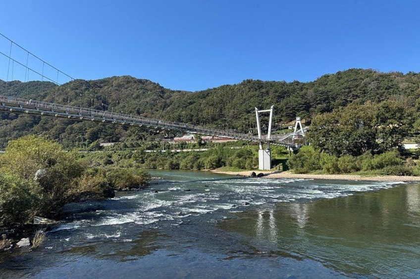 Un río con un puente, una montaña y un bosque. 2
