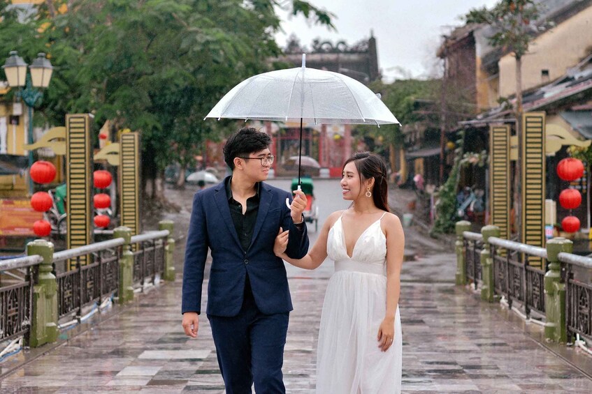 A couple walking on a wet street with traditional architecture and red lanterns. 5