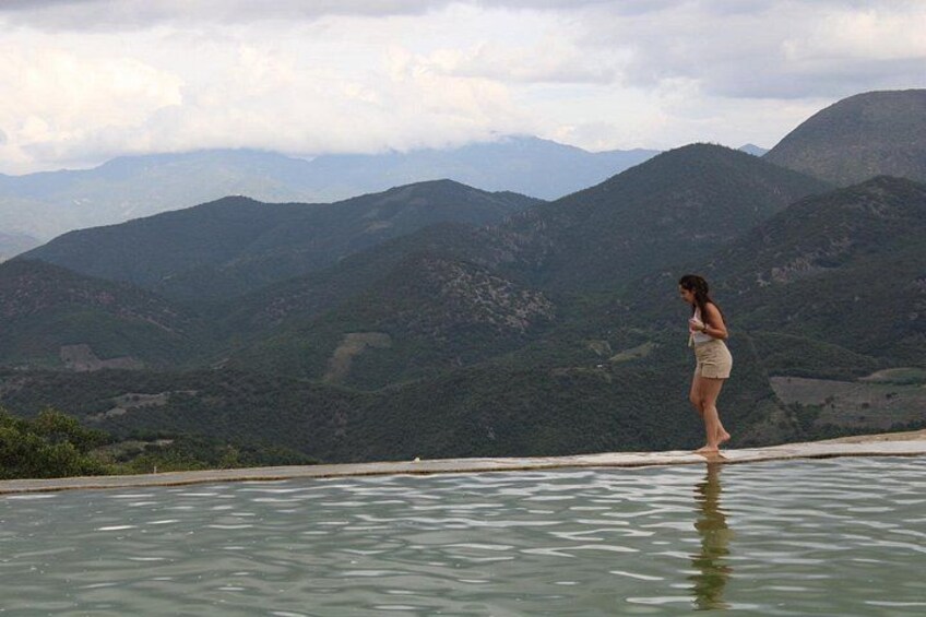 A woman standing by a pool with a mountainous landscape in the background. 4