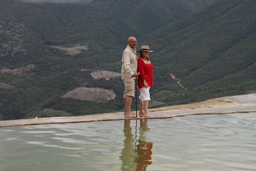 Two people standing on a reflective water surface with a mountainous landscape in the background. 5