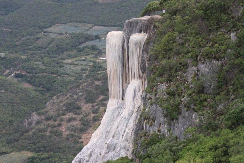 A waterfall cascading down a steep cliff surrounded by lush greenery. 3