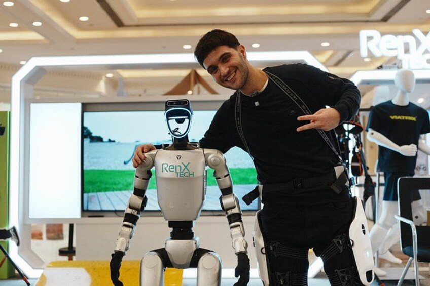 A person standing next to a robot with the text 'RenX TECH' on it. 1
