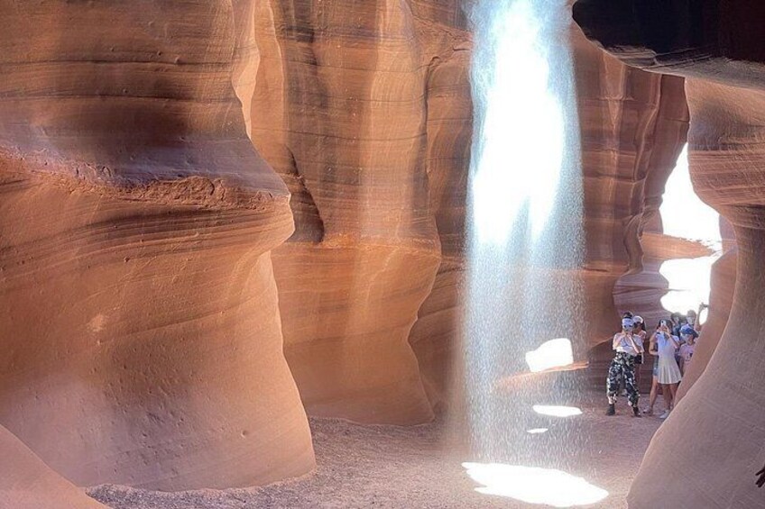 A canyon with layered rock formations and a group of people standing in the middle. 1