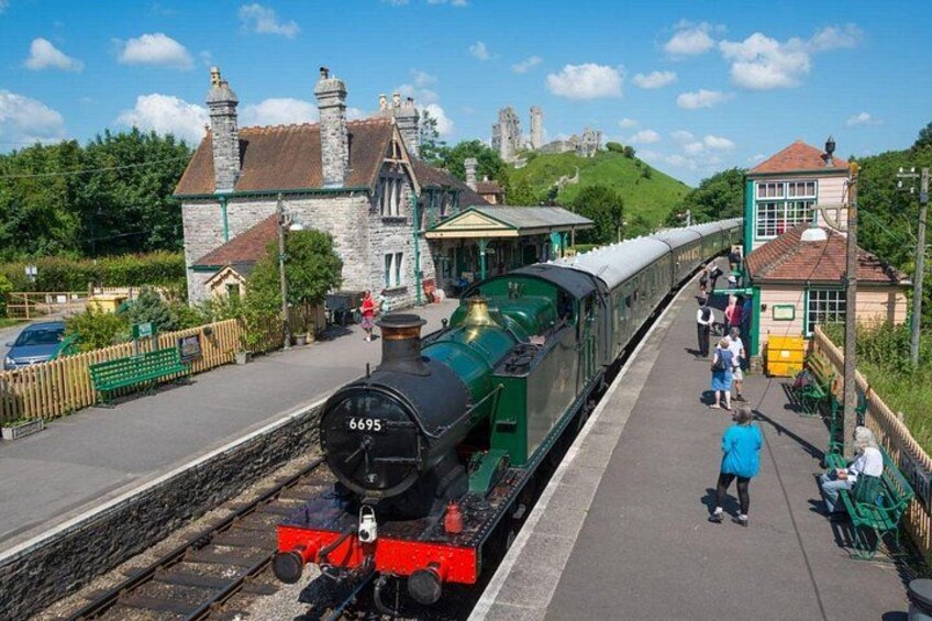 A steam locomotive at a station with a castle in the background. 5