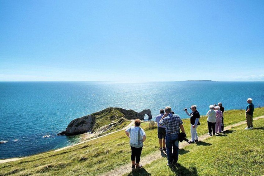 A group of people walking on a grassy hill overlooking a body of water. 3