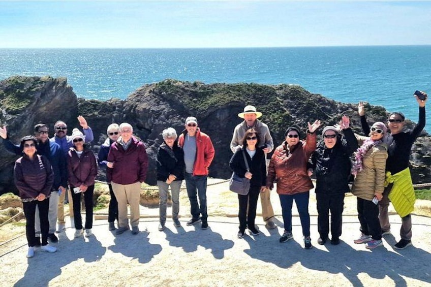 A group of people standing on a rocky outcrop with the ocean in the background. 4