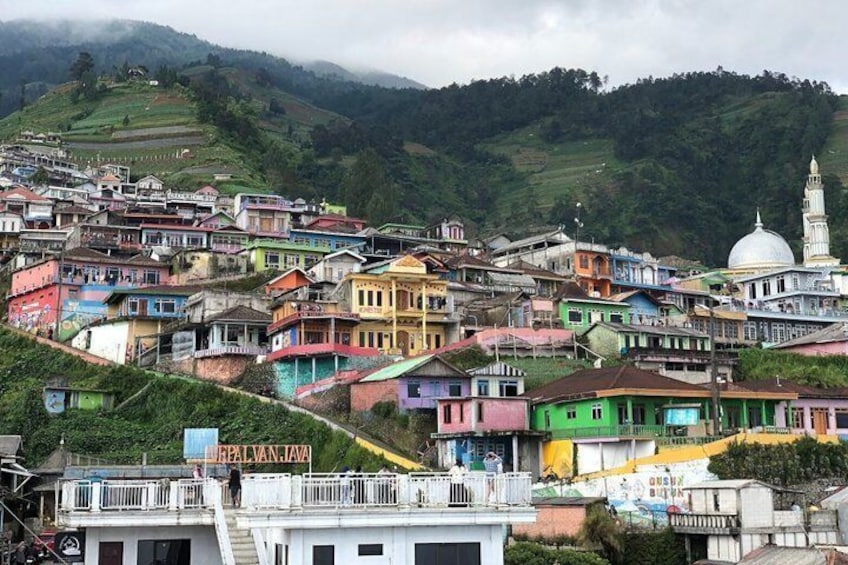 Un pueblo en una ladera con casas coloridas y un edificio de cúpula blanca. 3
