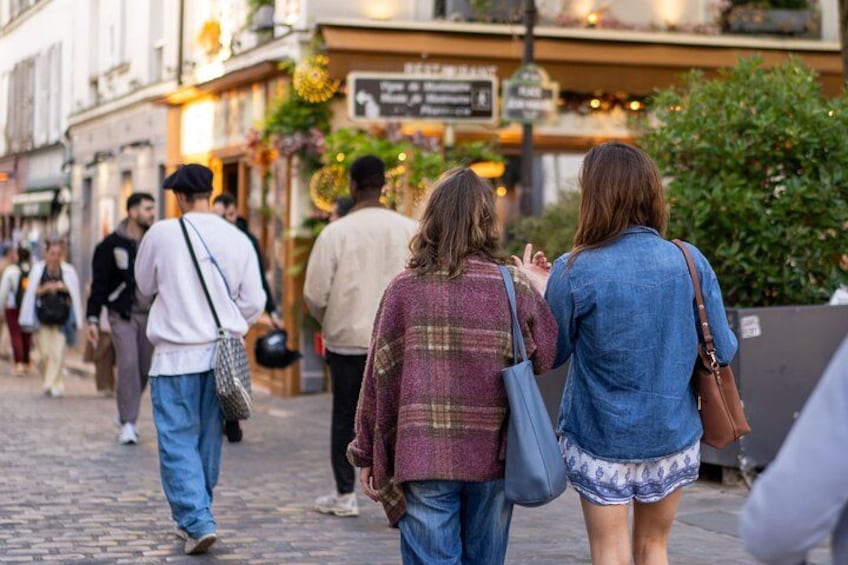 Eine Kopfsteinpflasterstraße mit Fußgängern, Geschäften und einem Schild. 4
