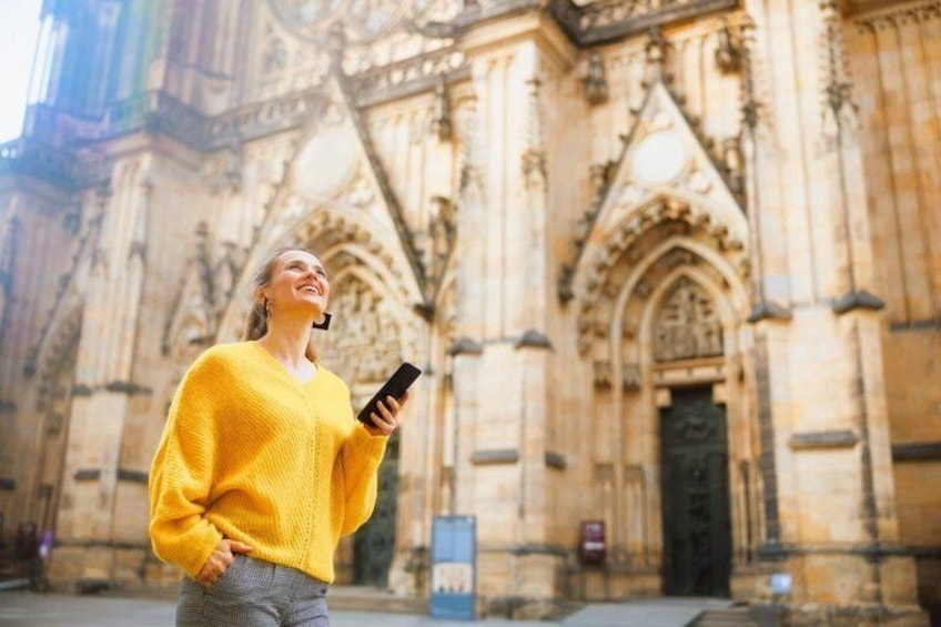 Eine Person in einem gelben Pullover vor einem historischen Dom mit aufwendiger Architektur. 1