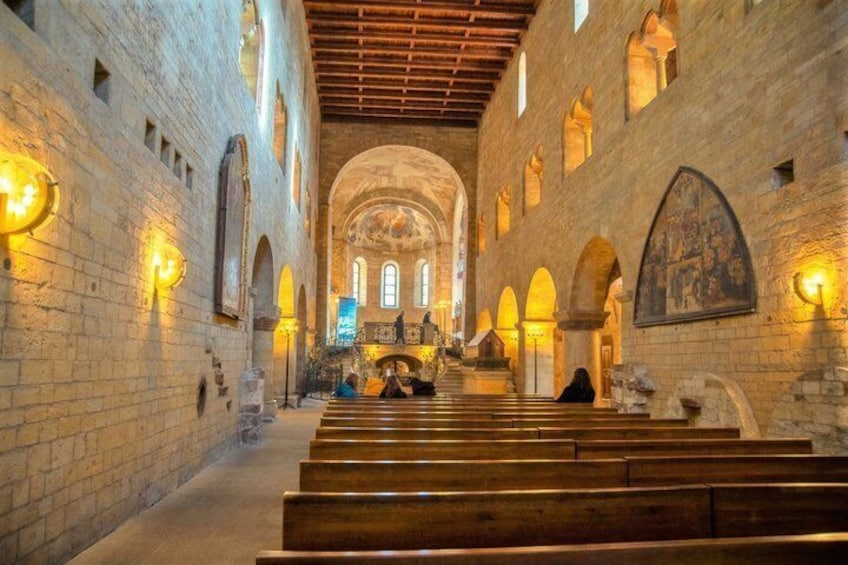 Ein Kircheninneres mit Gewölbedecken, Holzbänken und Steinwänden. 5