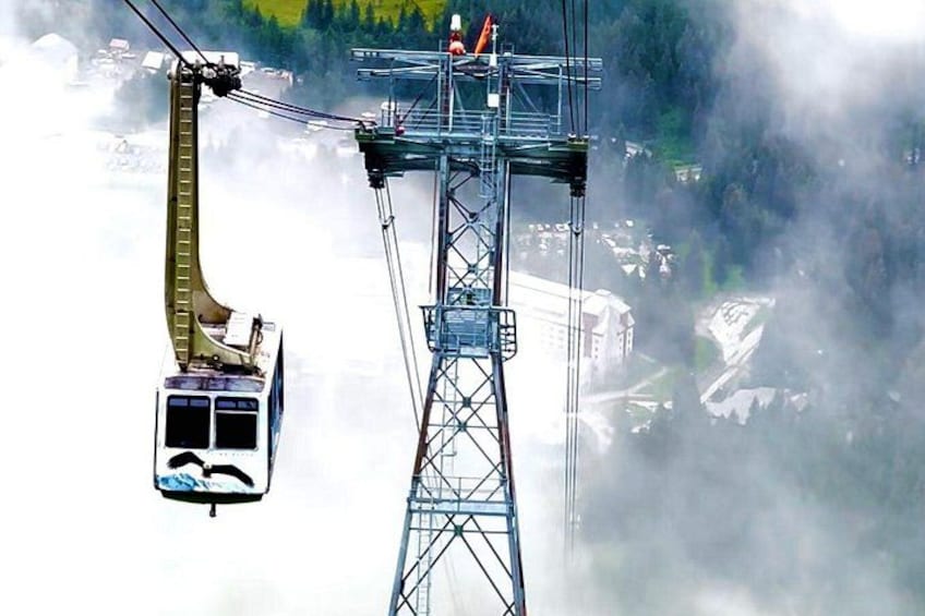 Eine Seilbahnsystem mit einer Gondel, die zwischen zwei Türmen schwebt, eine verschneite Landschaft und eine neblige Atmosphäre. 3