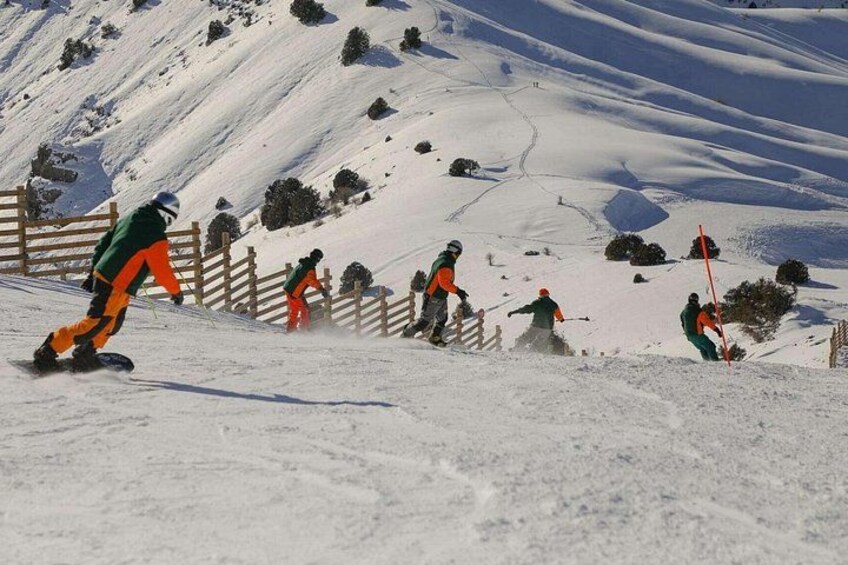 Skiers on a snowy slope with a wooden fence and trees in the background. 2