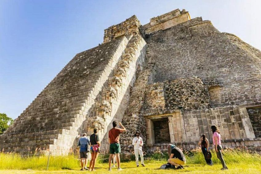 A pyramid-like structure with a staircase leading to the top, surrounded by grass and a few people. 3