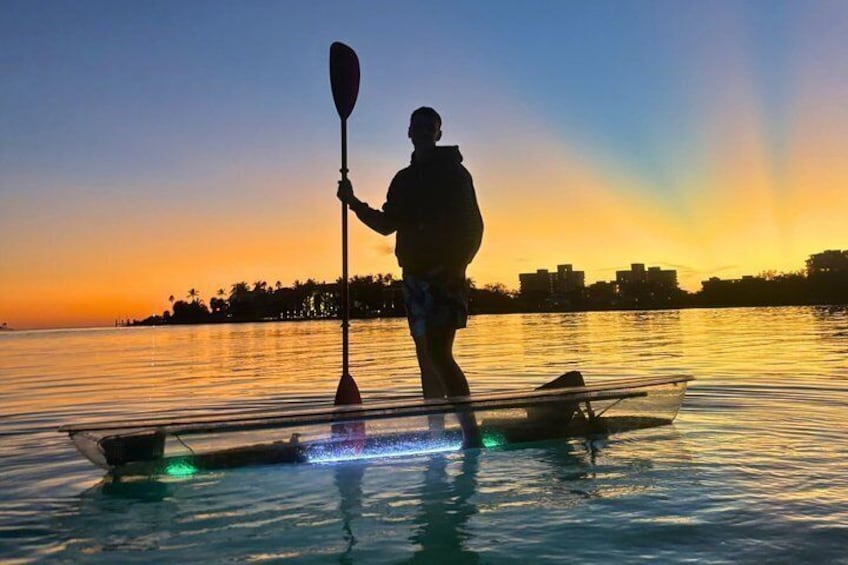 A person kayaking at sunset with city skyline in the background. 2
