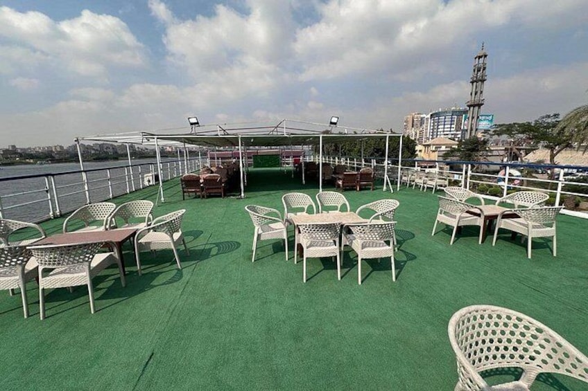 A deck with outdoor seating, a covered area, and a view of a cityscape with a prominent tower. 2