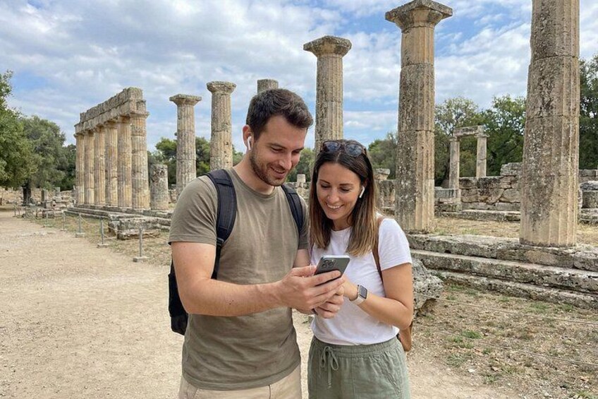 Two people standing in front of ancient ruins with columns. 5