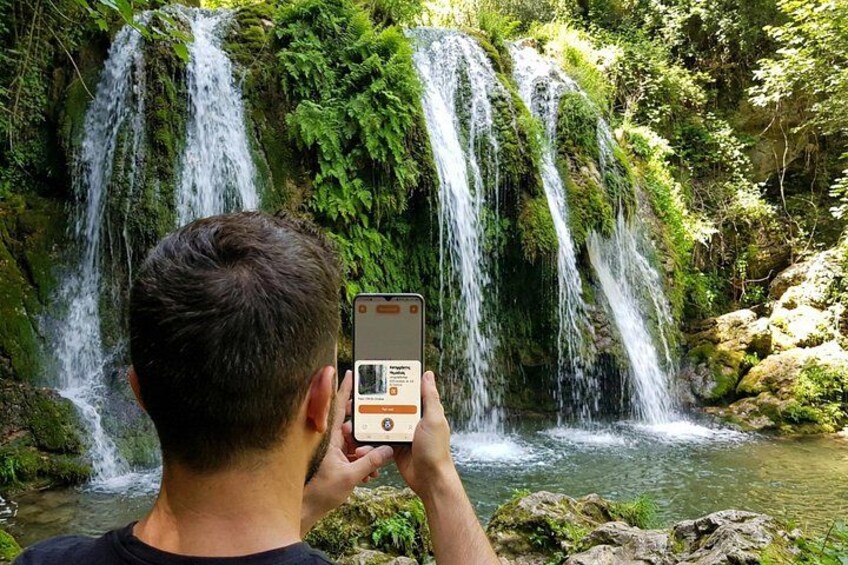 A person taking a photo of a waterfall with a smartphone. 3