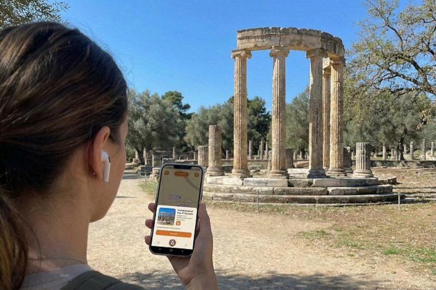 A person using a smartphone with a historical site in the background. 1