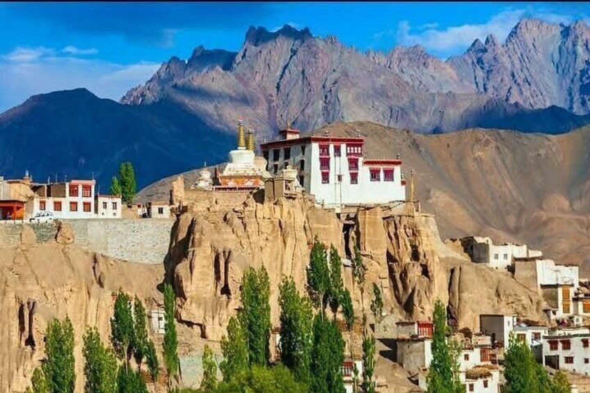 A monastery on a cliff with mountains in the background. 4