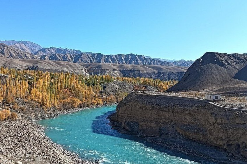 A river winding through a mountainous landscape with autumn-colored trees and a clear blue sky. 3