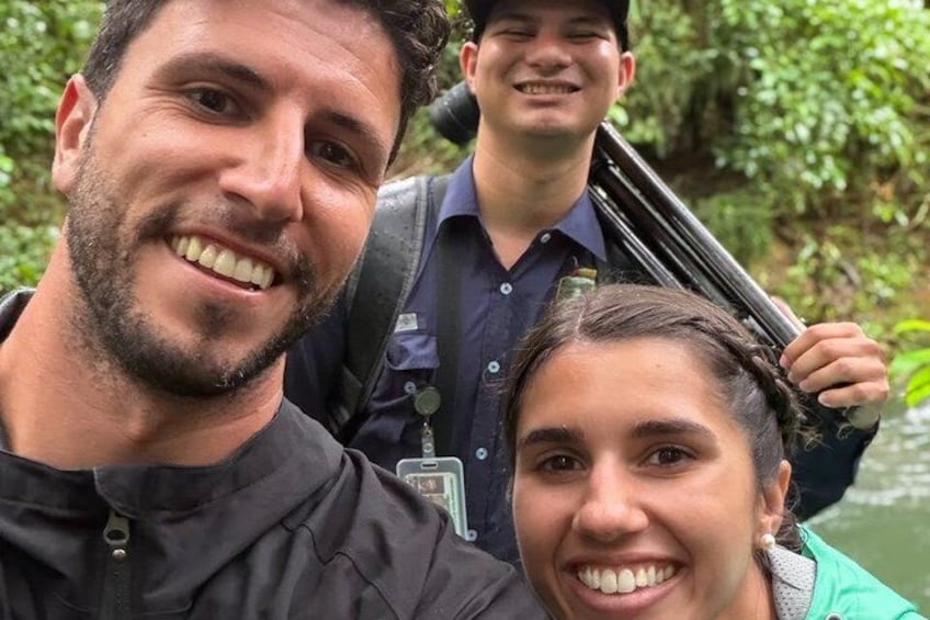A group of people in a natural setting with dense foliage in the background. 3
