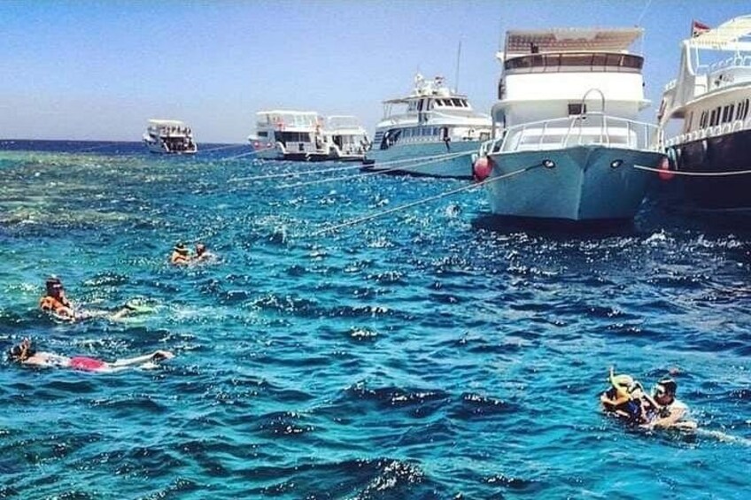 A clear blue sea with several boats and people swimming. 3