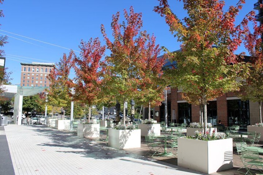 A plaza with trees, outdoor seating, and a building in the background. 3
