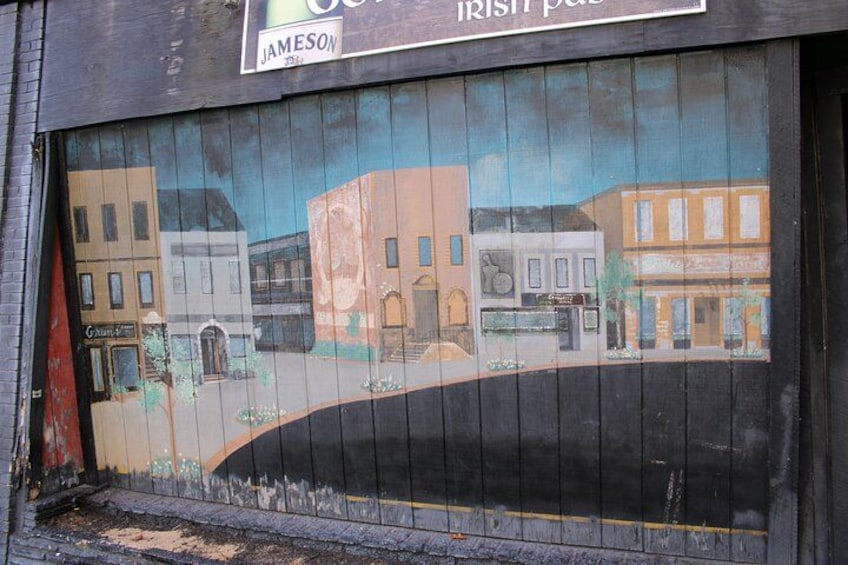 A mural of a street scene with buildings and a curved road. 3
