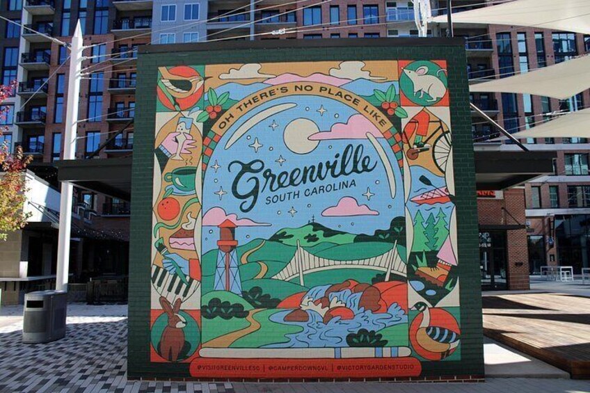A colorful mural with the text 'Greenville South Carolina' and various illustrations of local landmarks and activities. 1