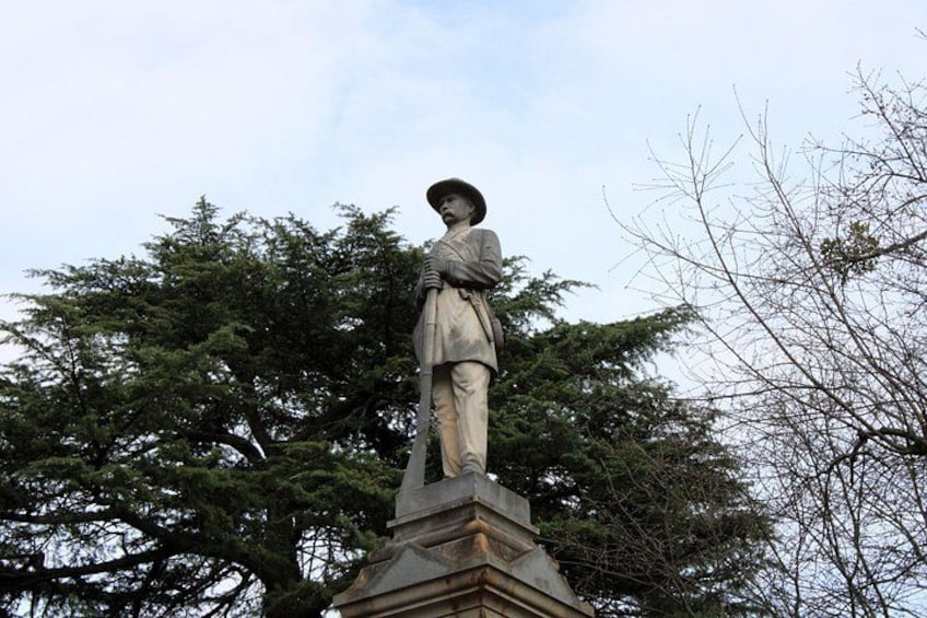 A statue of a person standing on a pedestal, surrounded by trees. 2