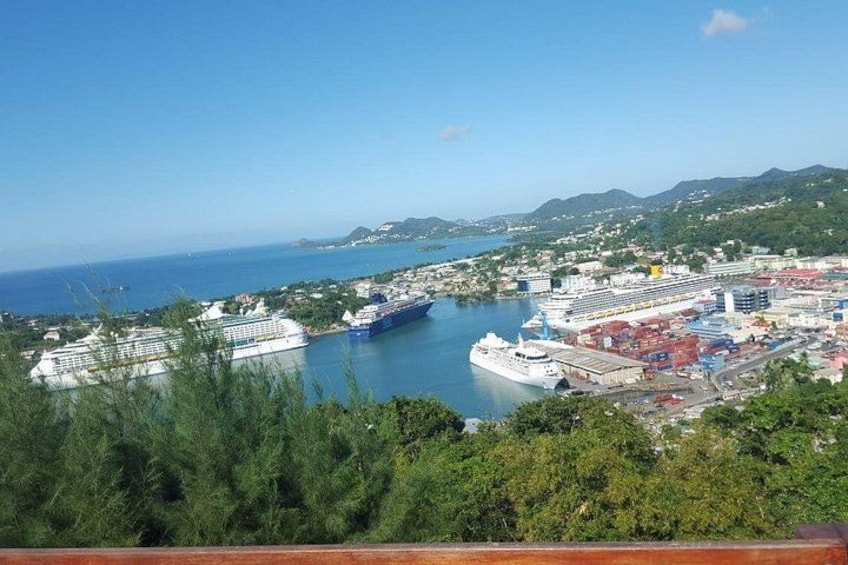 A coastal city with a large cruise ship docked, a harbor with cargo containers, and a mountainous landscape in the background. 1