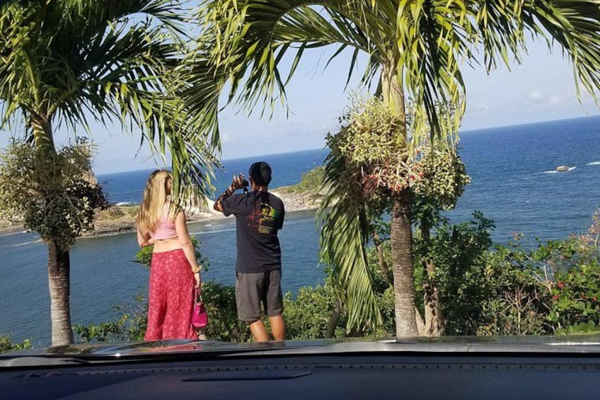 Two people standing by a coastal road, overlooking the ocean. 4