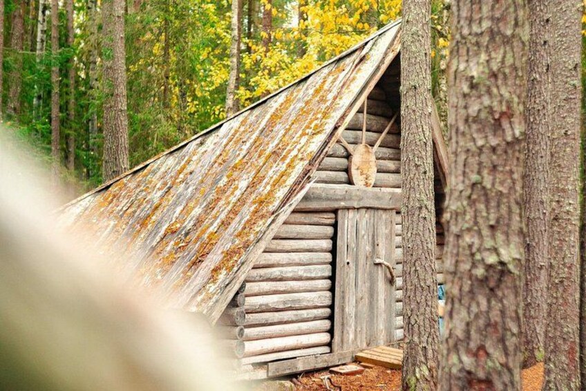 A rustic wooden structure with a slanted roof, surrounded by trees and foliage. 5