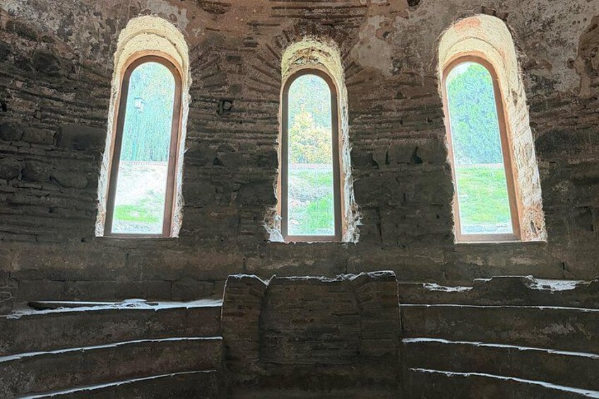 Ein altes Steinhaus mit drei Rundbogenfenstern und einer zentralen Treppe. 1