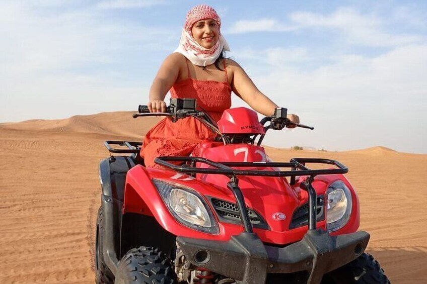 A person riding a red ATV in a desert with sand dunes. 4