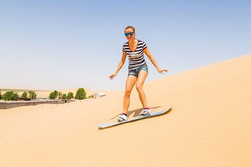 Une personne se tient debout sur une dune de sable, tenant une planche, et porte des vêtements rayés et un short. 2