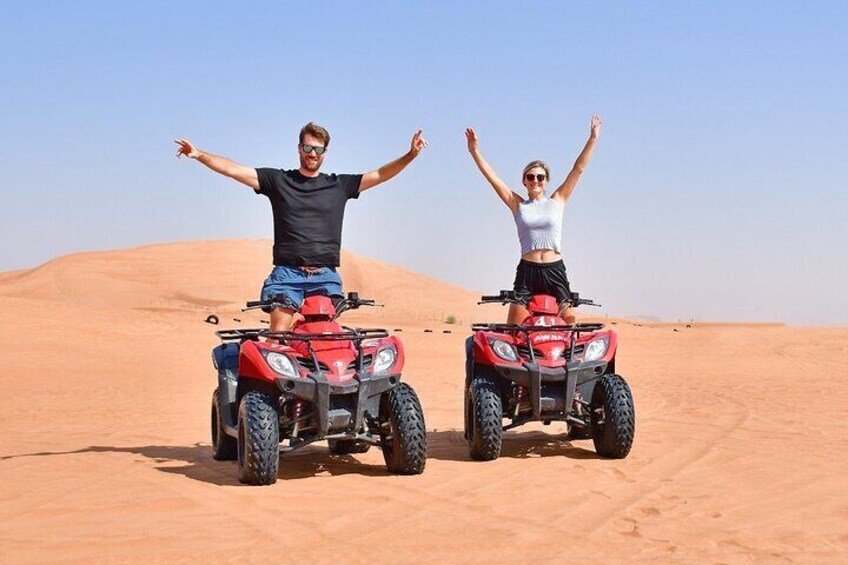 Two people on red ATVs in a desert with sand dunes. 5