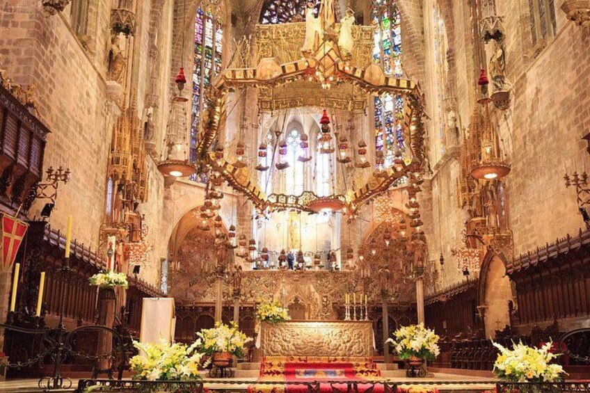 Een versierd kerkinterieur met een centraal altaar, glas-in-loodramen en bloemdecoraties. 3