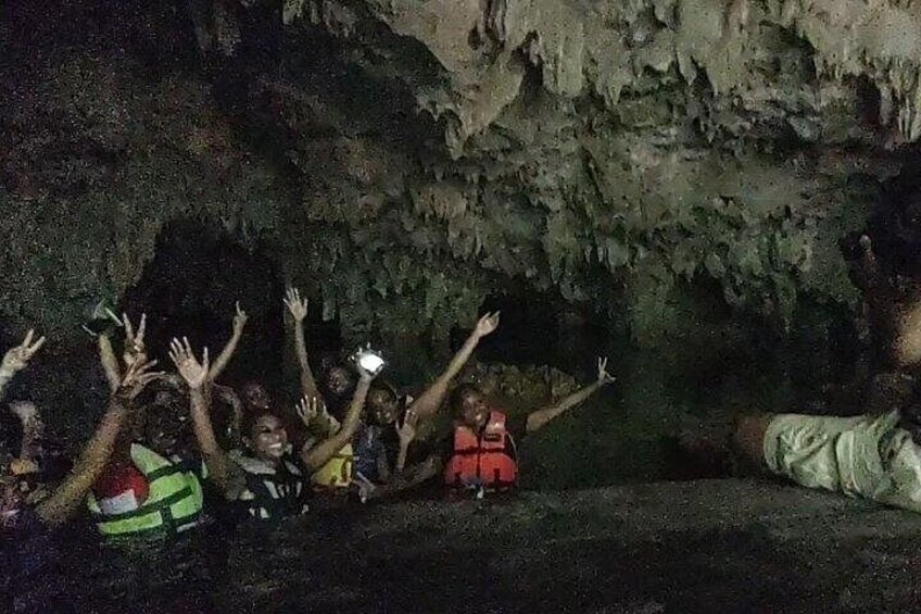 A group of people inside a cave with their hands raised. 3