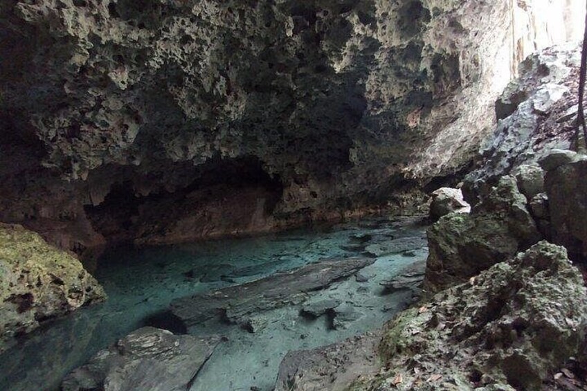 A cave with a turquoise pool surrounded by rocky formations. 2