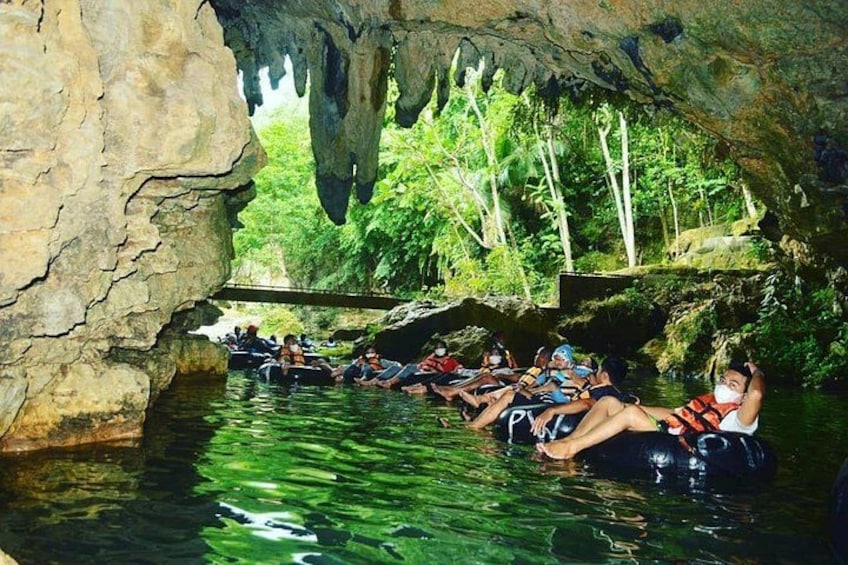 People floating in a cave with water, surrounded by greenery. 5
