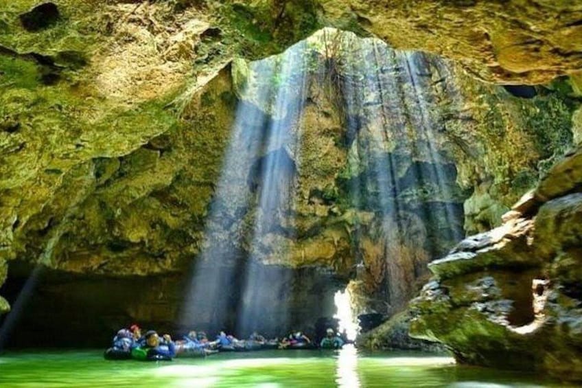A group of people rafting in a cave with water flowing down from above. 3