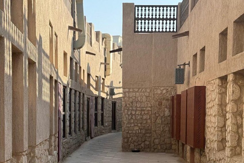 Un callejón estrecho con muros de piedra y contraventanas de madera, que conduce a un patio con una fuente. 3